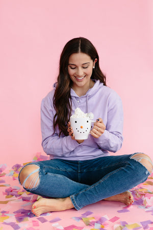 Park and Buzz radiance stud. Sparkle ball earrings. Hillberg and Berk. Canadian Brand. Glitter ball earrings. Rose Gold earrings jewelry jewellery. Girl in lilac hoodie sweatshirt holding snowman ug with hot chocolate and whipped cream. Wearing ripped jeans. Pink background with colourful confetti. Fun photo idea.